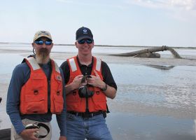 NOAA staff stand at the bow of an airboat while the dredge pipe feeds the Long Point Bayou marsh restoration project with sediments from the Calcasieu Ship Channel. Credit: NOAA