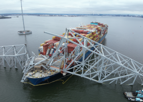An aerial view of bridge section that lies across the bow of a large container ship after collapse. 