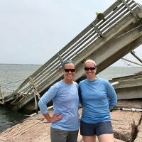 Two women standing in front of a collapsed structure. 
