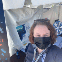 A person in a mask standing under a tent.