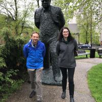 Two people posing for photo in front of a statue.