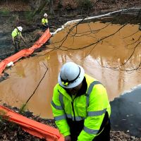 Pool of muddy water surrounded by boom.