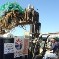 Forklift truck loading nets into a disposal bin.