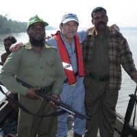 Gary Shigenaka (center) with two unidentified guards standing on a small vessel on the water.