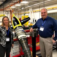 Two people posing next to large underwater glider.