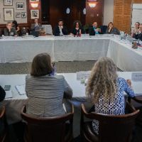 Large group sitting at tables arranged in a square.