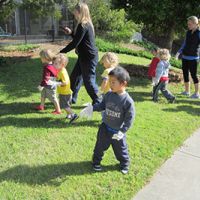 Toddlers, wearing gloves, walk aside with two adults.