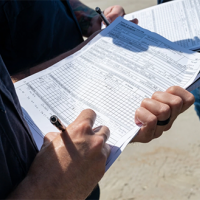 A student shown writing notes on shoreline conditions on a SCAT form as part of participation in NOAA’s SCAT training.