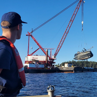 A Coast Guard member watches the F/V Aleutian Isle being lifted onto a barge off San Juan Island on Sept. 21, 2022. Image credit: U.S. Coast Guard.