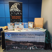 The NOAA Marine Debris Program table at the Summit, showcasing materials and outreach activities related to the prevention, research, and removal of marine debris. The table also included funding opportunity information from both the Marine Debris Program and National Sea Grant Office related to marine debris opportunities (Credit: NOAA).