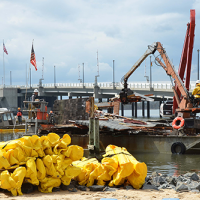 Marine debris caused by demolition of a home destroyed by Hurricane Sandy being removed from entering further into Barnegat Bay (Photo: Federal Emergency Management Agency).