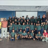 A group of young students pose for a group photo in a classroom setting.