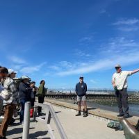 A group of trainees listen to a trainer deliver a lesson from a Seattle shoreline.