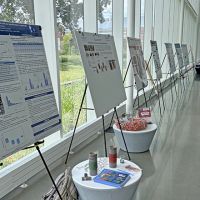 Posters presented on easels lined up in a row down a university hallway.