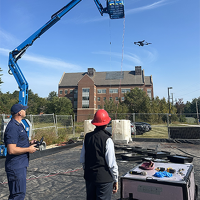 Drone pilot flies drone pilot demonstrates flying drone over oil in plastic tubs to detect oil pollution.