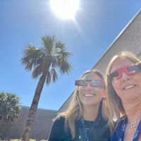 Two NOAA Marine Debris Program staff snap a selfie outside donning eclipse glasses.