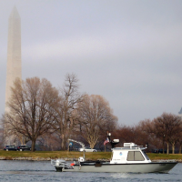 A boat on water with a monument on the shoreline in the background.