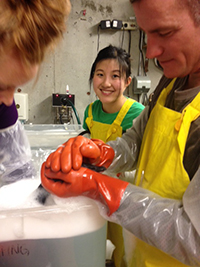 Three people help wash an oiled goose in big soapy wash tubs.