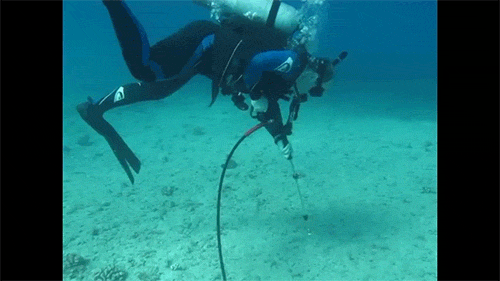 SCUBA diver using a power washer to clear a spot on the seafloor for the cement and coral to stick to during coral restoration after the VogeTrader ship grounding.